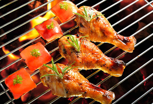 Grilled chicken leg on the flaming grill.