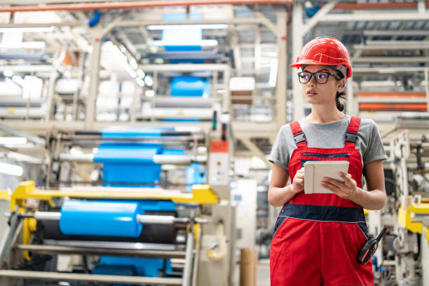 istock Focused female worker checks tablet for processes in expansive modern manufacturing plant. 2192613347