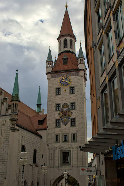 Munich, Germany - October 22, 2024: A striking medieval gate tower with its ornate clock and heraldic crest in Munich. The weathered stone and steeply pitched roofs evoke a sense of timelessness.
