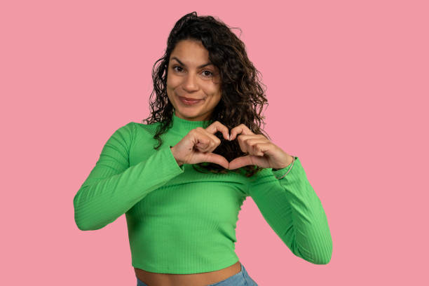 istock Young woman making heart shape with hands on pink background 2192616174