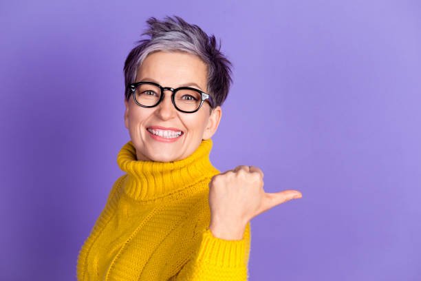 istock Photo of shiny attractive lady dressed yellow pullover showing thumb back empty space isolated purple color background 2192620578