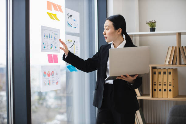 istock Asian businesswoman analyzing charts at office window 2192621654