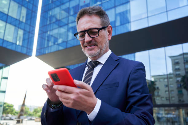 istock Mature businessman using mobile phone sending messages smiling. 2192623651