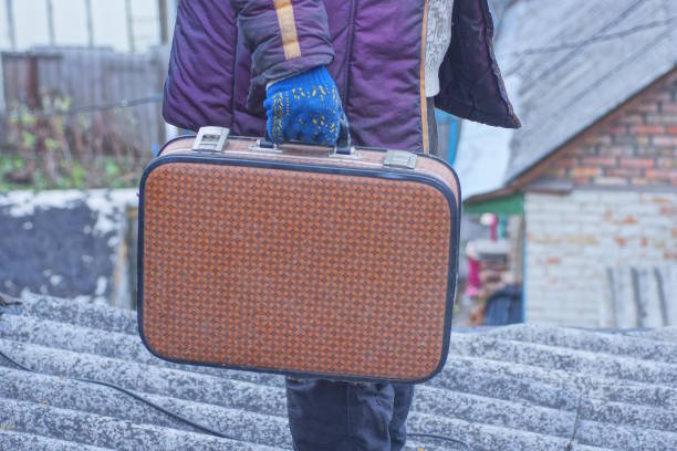 one man holding old brown leather suitcase in hand on autumn street