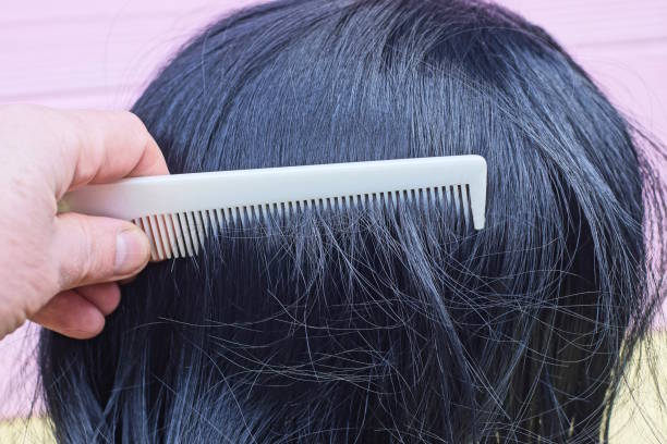 istock hand with white plastic comb combing black long hair on wig 2192625459