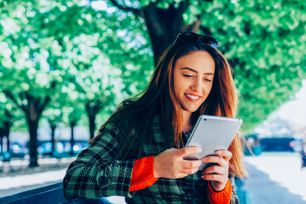 istock Beautiful woman sitting at bench and reading an e-book 2192633142