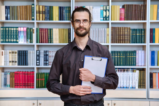 istock Portrait young male with clipboard in library 2192641062