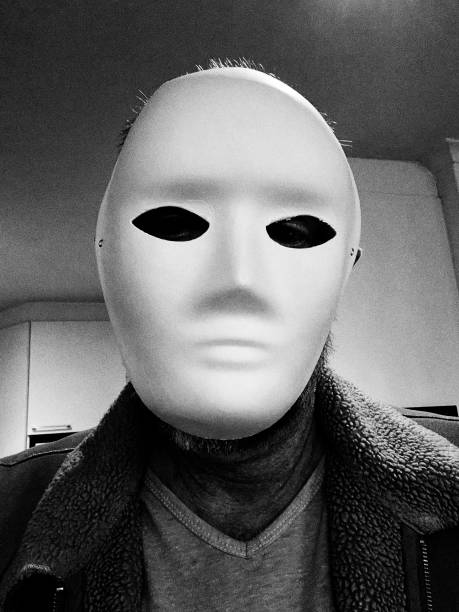 Like a scene from a horror movie, a mystery man wearing a white mask with a blank expression looks down at you.