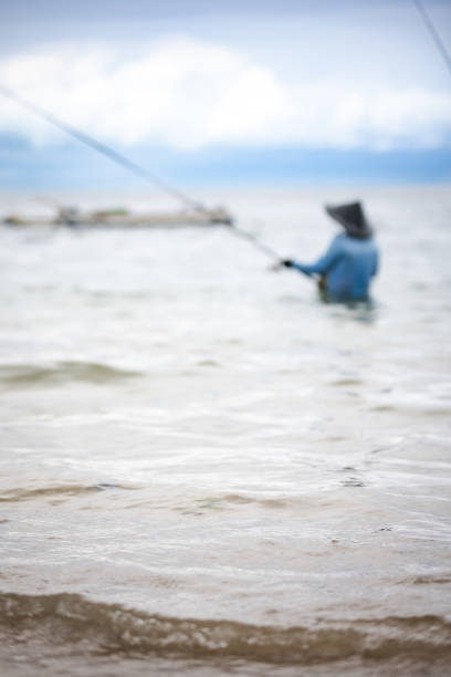 Fisherman is fishing in the ocean at Sanur beach.Bali island - Indonesia.