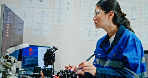 istock Young female engineer using multimeter and soldering tools to test and repair robotic arm in tech lab. AI and Robotics Development. 2192647114
