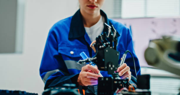 istock Closeup Young female engineer using multimeter and soldering tools to test and repair robotic arm in tech lab. AI and Robotics Development. 2192647115