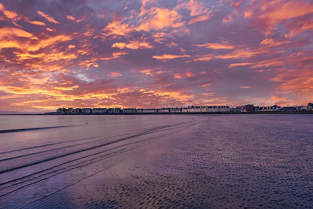 Troon out on the bay at sunset. Troon from the Bay looking over the sand towards the residential properties in tyhe far distance and at sun set. beach fire scotland stock pictures, royalty-free photos & images