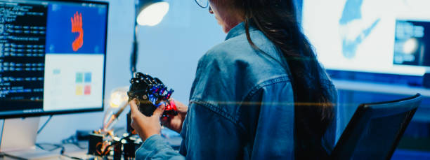 istock Closeup Young female engineer working late on robotic arm prototype in tech lab at night. Machine learning, computer manufacturing, innovation and creativity. AI and Robotics Development. 2192648923