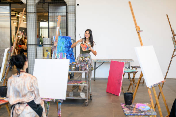 istock Art teacher explains to students how to mix paint on a palette 2192650483
