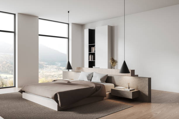 istock Minimalist modern bedroom with a cozy bed, pendant lights, and large windows overlooking a scenic landscape in natural tones. 3D Rendering 2192653217