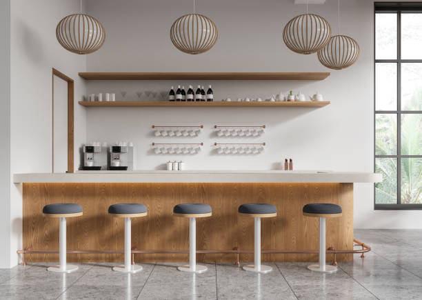 istock Minimalist cafe interior with stools, coffee machines, and modern hanging lights, featuring wooden shelves and neutral tones on a clean background. 3D Rendering 2192656522