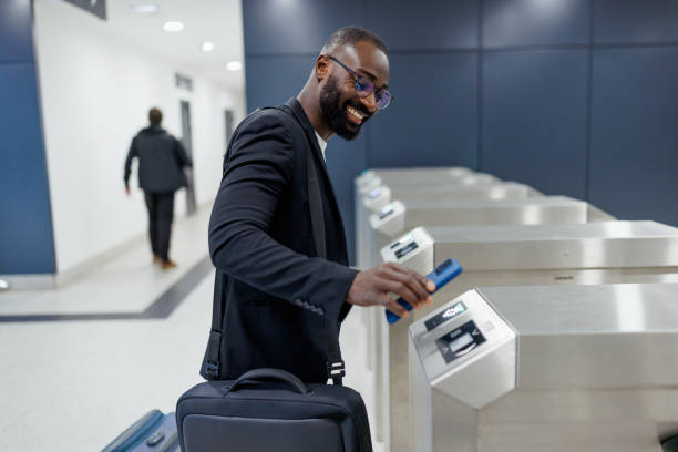 Businessman using smartphone to pass electronic ticket gate at airport