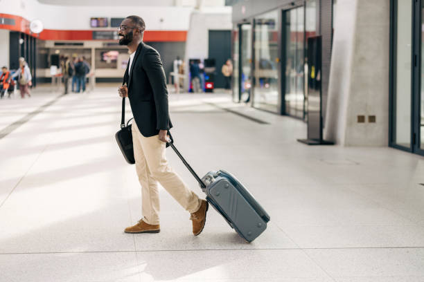 istock Businessman walking through airport terminal pulling suitcase 2192657791