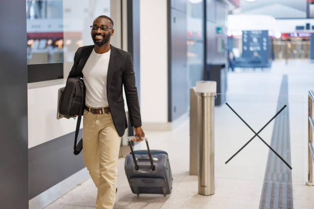 istock Businessman walking through airport terminal pulling suitcase and carrying laptop bag 2192658096