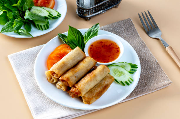 istock Fried spring rolls, vegetables and tomatoes arranged  on an orange table with dipping sauce. 2192661259