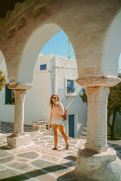 Woman exploring Greek architecture during island hopping, shot on camera film with vintage feel