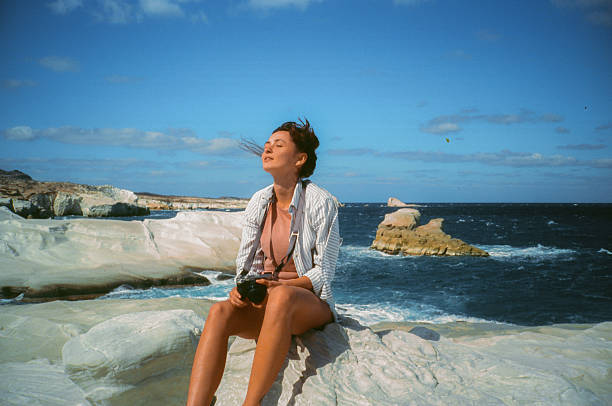 Woman with camera exploring white rocks on Milos island, Greece shot on film with vintage vibe