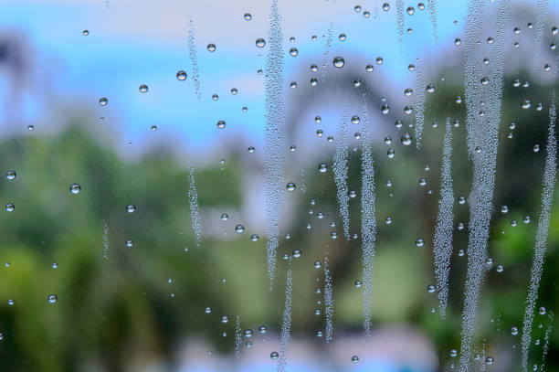 rain drops during raining in rainy day outside window glass with blurred background with water droplet flow down the surface