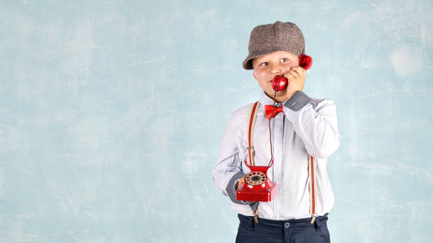 active boy wearing business suit and red bow and he is talking in a red vintage phone, ready for business