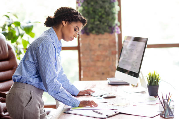 istock Focused young businesswoman working diligently in a modern office setting, dressed in a sleek formal shirt and glasses 2192665235