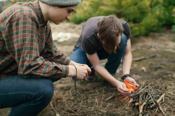Teenagers setting a campfire together  spending time in nature
