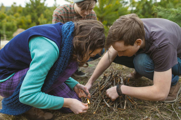 Teenagers setting a campfire together  spending time in nature
