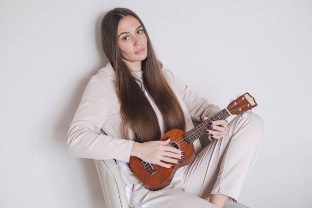 istock Woman with ukulele sitting on a chair. 2192667881