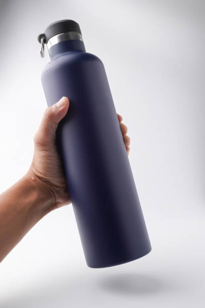 istock Someone hand is holding matte dark blue colored drinking bottle. Reusable water bottle container. Thermos travel tumbler. Insulated drink container. Isolated on white background. 2192671529