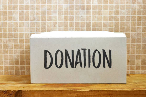 Donation Box on Wooden Surface with Text Against a Tiled Wall