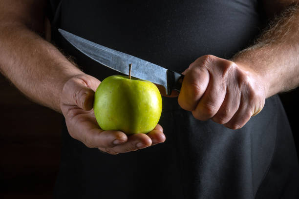 istock A skilled hand grips a bright green apple while preparing to slice it with a sharp knife. The atmosphere is filled with an inviting kitchen vibe, emphasizing freshness and culinary creativity 2192673062