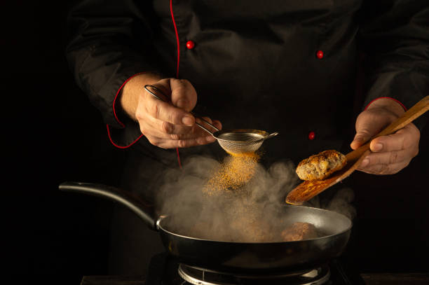 istock Under the warm glow of kitchen lights, a skilled chef sprinkles fragrant spices into a sizzling pan. The air fills with the enticing aromas of culinary creativity and passion at sunset 2192673301