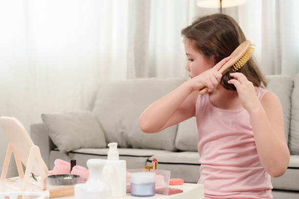 istock Young girl using brush on hair during creative beauty activity in cozy home setting. Playful moment highlighting childhood curiosity, self-expression, and learning hairstyling techniques. 2192676878