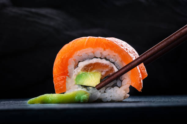 istock Salmon sushi with avocado and cream cheese, uramaki roll on a black background 2192682807