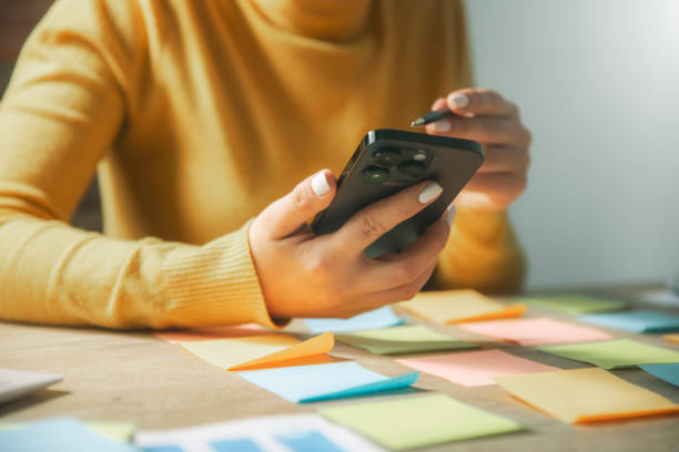 istock a woman sitting at a table with a cell phone 2192683430