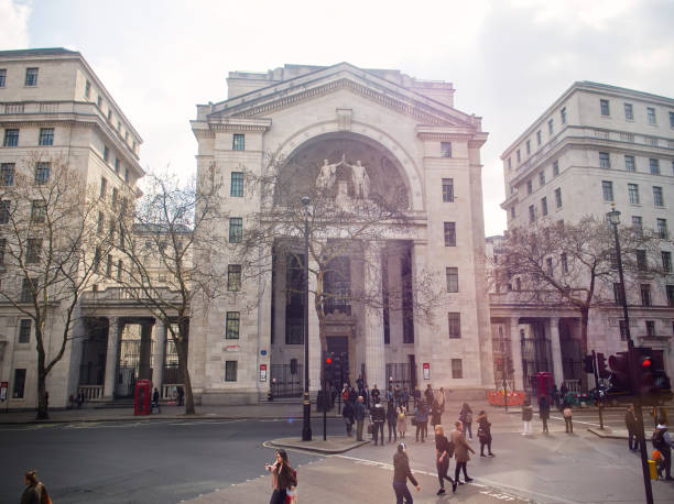 London, United Kingdom - March 28, 2019: Imposing neoclassical architecture with arched entrance, surrounded by pedestrians in urban setting