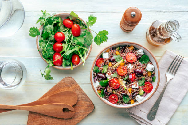 Quinoa salad, healthy Mediterranean lunch with fresh organic vegetables, cheese, and olives, overhead flat lay shot while cooking