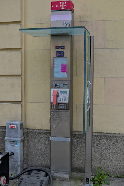 Munich, Germany - October 22, 2024: A modern public phone booth in Germany. It is located against the wall of a building on Odeonsplatz in Munich. The weathered payphone belongs to Deutsche Telekom.