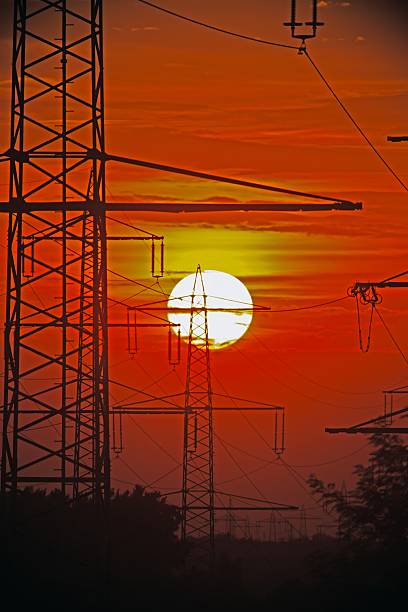 Power transmission towers silhouetted against a sunset sky