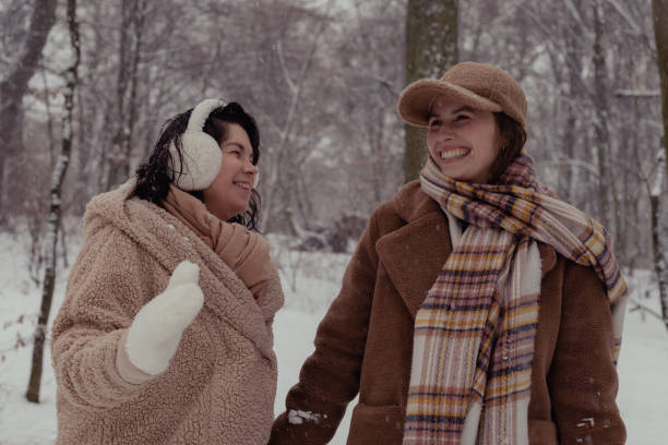 Portrait of girl with big snowflakes on her hair and hood. Young model wearing a parka in winter. Cold, winter jacket and fun in the mountains.
