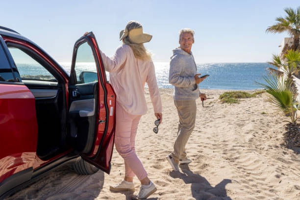 Mature couple leave car parked on beach