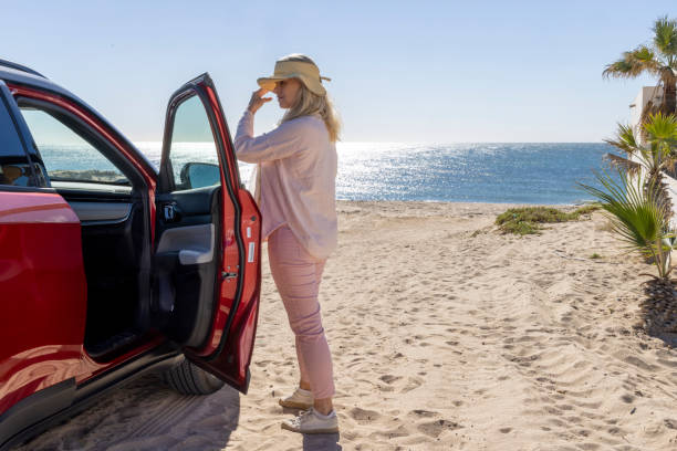 istock Mature woman pauses by car on beach 2192686924