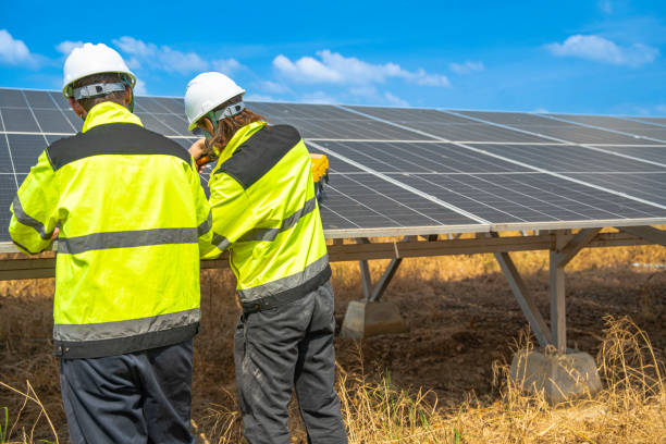istock Team engineers in a high visibility jacket performs an inspection on the underside of a solar panel installation at a solar farm, emphasizing renewable energy infrastructure under bright skies. 2192688109