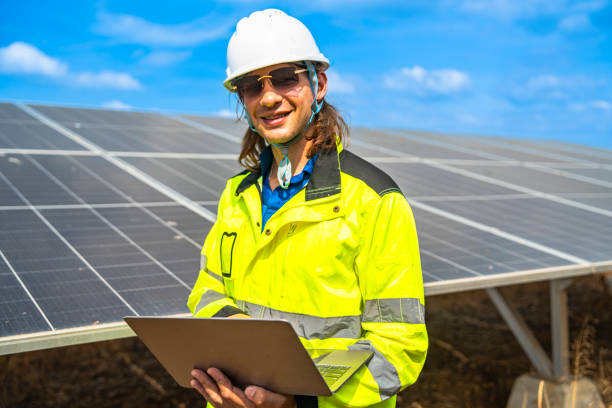 istock A confident solar energy technician, wearing a helmet and reflective jacket, stands with arms crossed in front of an array of photovoltaic panels, under a bright and clear blue sky. 2192689254