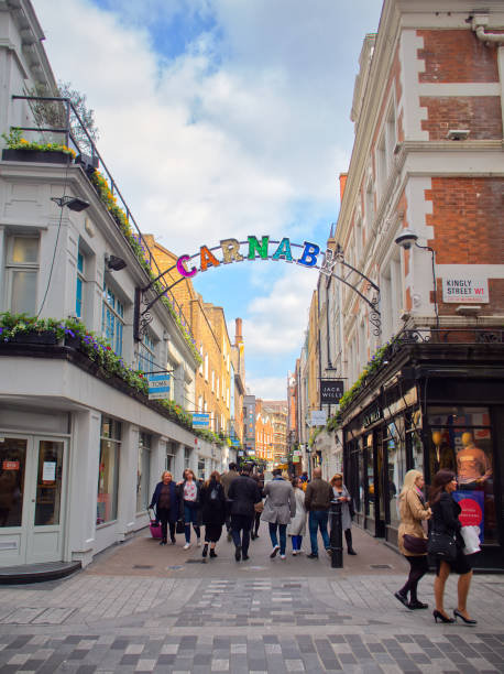 London, United Kingdom - March 28, 2019: Bustling pedestrian shopping street with colorful 'Carnaby' sign and historic buildings