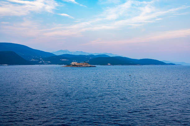 A panoramic shot of Kotor Bay, Montenegro, surrounded by dramatic mountains and picturesque coastal towns. The calm water reflects the beauty of the lush green slopes and serene Mediterranean atmosphere